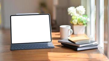 Laptop with a notebook and coffee on a wooden table in the office with beautiful lighting. photo