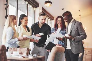 Successful young business people are talking and smiling during the coffee break in office photo