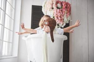 Portrait of a girl and a boy in pilot hat playing in bathroom at pilots or sailors. The concept of travel, childhood and the realization of dreams photo