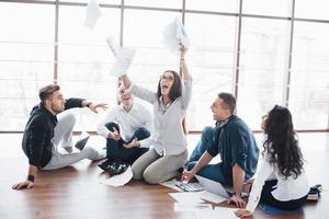 Young creative people in modern office. Group of young business people are working together with laptop. Freelancers sitting on the floor. Cooperation corporate achievement. Teamwork concept photo