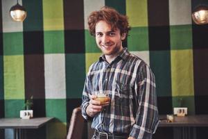 Funny guy holding a glass of whisky and posing against vintage wallpaper photo