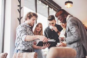 Successful young business people are talking and smiling during the coffee break in office photo