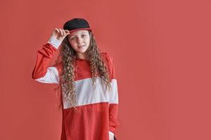 Young urban woman dancing on red background, modern slim hip-hop style teenage girl photo