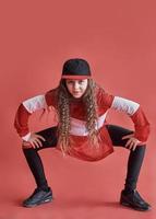 Joven hermosa linda chica bailando sobre fondo rojo, moderno y delgado estilo hip-hop adolescente saltando