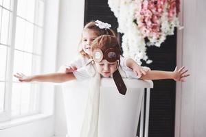 Portrait of a girl and a boy in pilot hat playing in bathroom at pilots or sailors. The concept of travel, childhood and the realization of dreams photo