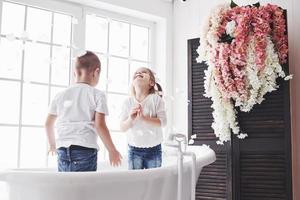 Child playing with rose petals in home bathroom. Little girl and boy fawing fun and joy together. The concept of childhood and the realization of dreams, fantasy, imagination photo