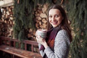 oman wearing warm knit clothes drinking cup of hot tea or coffee outdoors
