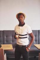 Moda hombre afroamericano con sombrero con vaso de whisky foto