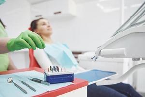 un paciente en una clínica dental se sienta en una silla y el médico prepara las herramientas para el tratamiento foto