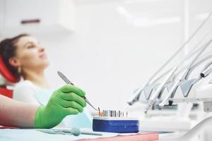 A patient in a dental clinic sits in a chair and the doctor prepares the tools for treatment photo