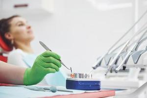 A patient in a dental clinic sits in a chair and the doctor prepares the tools for treatment photo