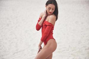 hermosa joven curtida en bikini rojo posando en la playa. Retrato de modelo sexy con cuerpo perfecto. concepto de vacaciones de verano foto