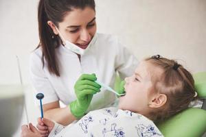 chequeo de dientes en el consultorio del dentista. Dentista examinando los dientes de las niñas en la silla del dentista foto