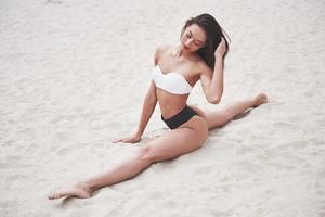 hermosa chica de lujo delgada en bikini en la playa de arena en una isla tropical. sexy cuerpo bronceado y figura perfecta foto