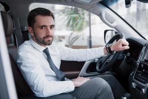 Confident young businessman sitting at the wheel of his new car photo