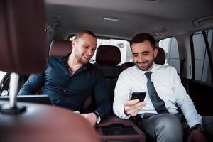 The two old business friends conclude a new agreement in an informal setting in the car's interior photo