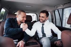 los dos viejos amigos de negocios concluyen un nuevo acuerdo en un ambiente informal en el interior del automóvil foto
