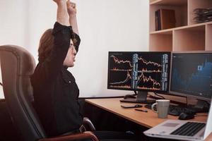 Young stock trader broker stretching hands at workplace, he first achieved great success on the stock market photo