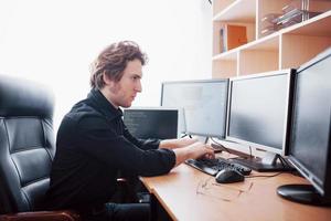 Male programmer working on desktop computer with many monitors at office in software develop company. Website design programming and coding technologies photo