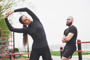 Young man and woman perform exercises and stretch marks before doing sports photo