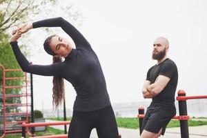 joven y mujer realizan ejercicios y estrías antes de hacer deporte foto