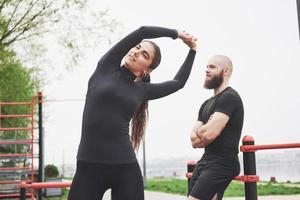 Young man and woman perform exercises and stretch marks before doing sports photo