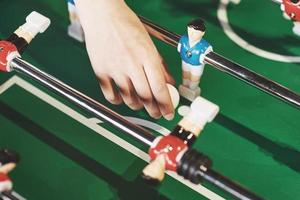 futbolín en el centro de entretenimiento. Imagen cercana de una niña lanzando una pelota de juguete en un juego de fútbol foto