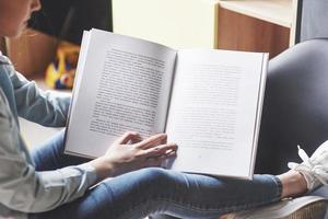 la vista es cercana, dos niñas leyendo un libro en un café o biblioteca foto