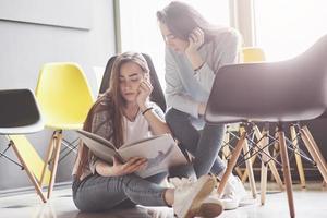 Two beautiful twin girls spend time read a book in library in the morning. Sisters relaxing in a cafe and having fun together photo