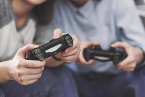 Twin sister sisters play on the console. Girls hold joysticks in their hands and have fun photo