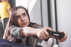 The woman is playing on the console and holding joystick in hands photo