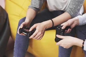 Twin sister sisters play on the console. Girls hold joysticks in their hands and have fun photo