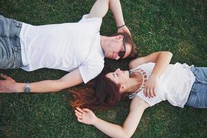 Romantic couple of young people lying on grass in park. They look happy. View from above. photo