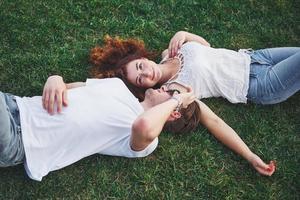 Romantic couple of young people lying on grass in park. They look happy. View from above. photo