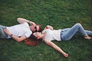Cheerful couple lying on the grass. Young people outdoors. Happiness and harmony. photo