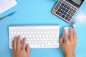 Hand working computer on table, Top view on working space with office equipment photo