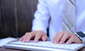 Businessman working on computer in office, typing keyboard photo