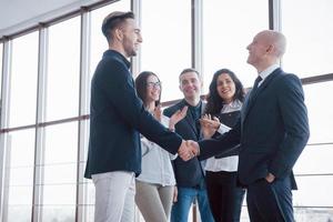 Dos hombre de negocios confiado dándose la mano durante una reunión en la oficina, el éxito, el trato, el saludo y el concepto de socio