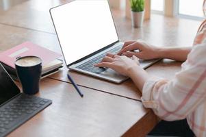 Close-up view of business woman hand is using a laptop on a table with coffee in the comfortable office. photo