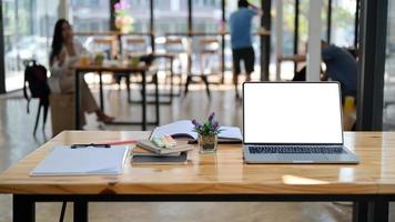 Cropped shot of laptop, notes and office supplies on a wooden desk in a comfortable shared workspace. photo