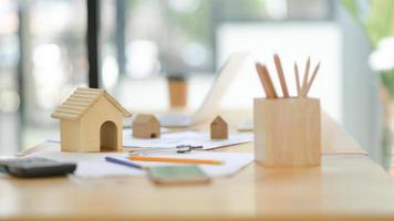 Mockup house drawing tools and wooden model house on desk in the office. photo