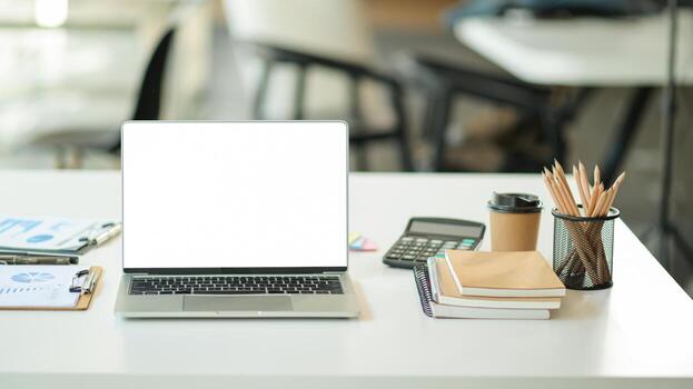 Blank screen laptop in modern workspace with office supplies. photo