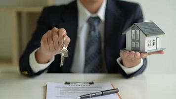 The house broker holds the keys and the model house in hand. Real estate concept. photo