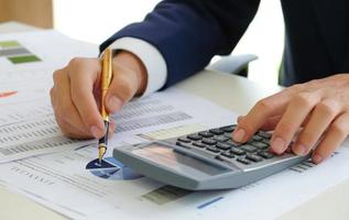 Cropped shot of Analysts use calculators and pointers on graphs to assess the fluctuating stock market situation. photo