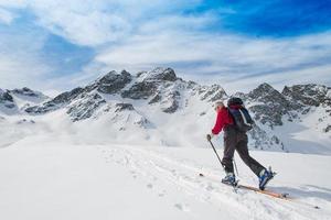 Elderly man sporting fit skis uphill climbing photo