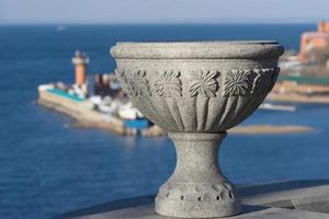 Decorative stone vase on the street of the city against the sea. photo
