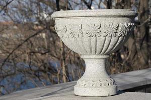 Decorative stone vase on the street of the city on tree branches photo