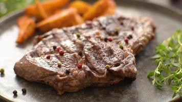 Delicious juicy fresh beef steak with spices and herbs on a dark concrete background video