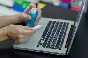 Spraying alcohol to clean the computer and wipe the germs. Health care concept. photo