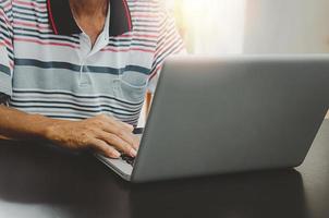 Mano de hombre usando computadora portátil en la mesa en casa, buscando información navegando por internet en la web, trabajo desde casa concepto de negocio. foto